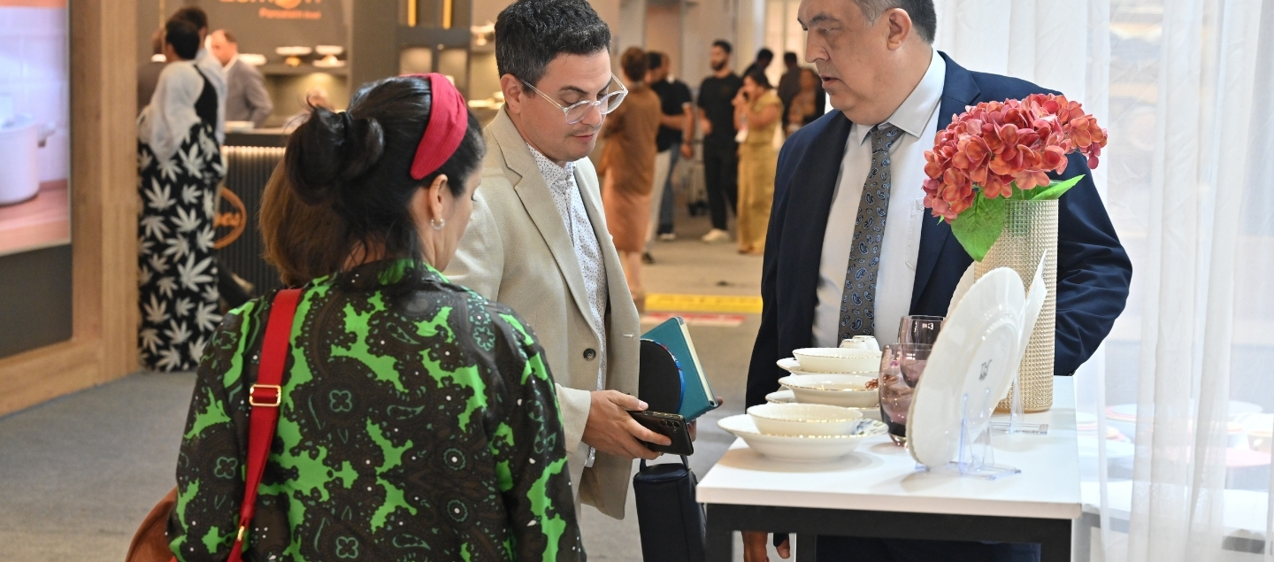 Visitors discuss products at the stand showcasing kitchenware, appliances, and visually rich table presentations.
