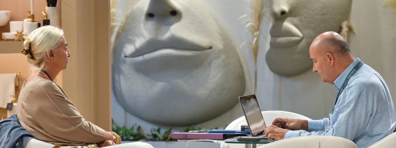 Two visitors sitting opposite each other next to a wall made of the shape of a face