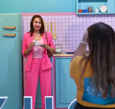 Geçtiğimiz yılki Zuchex etkinliğinde fotoğraflanan bir kadın, ziyaretçilerin katılımcılarla etkileşime girdiği ve çeşitli mutfak eşyalarını incelediği görüntü